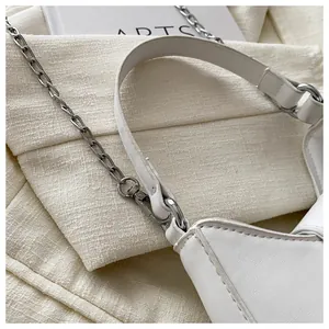 Détail d'un sac demi-lune blanc avec chaîne argentée et coutures fines sur cuir lisse