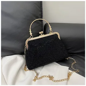 Close-up of black rhinestone clutch with floral gold handle and kiss-lock closure