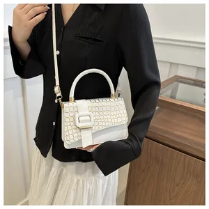 Detailed view of white textured square crossbody bag with gold buckle and shoulder strap
