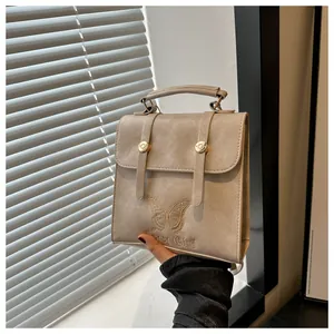 Close-up of butterfly embroidery and Fancy Club text on beige PU leather handbag