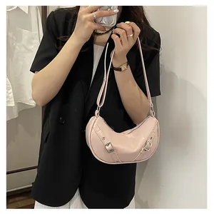 Close-up of a pink patent leather saddle bag worn by a model in a black blazer suit