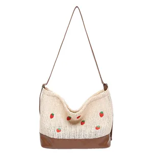 Straw woven bucket bag with embroidered strawberries and contrast brown leather strap