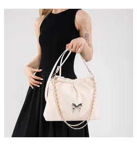 Détail du sac seau en PU blanc cassé avec fermoir papillon doré et design plissé