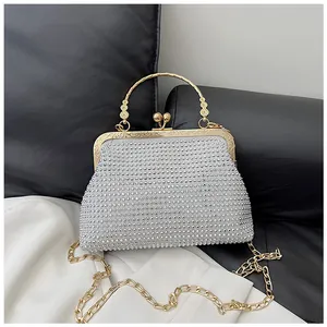 Detail of silver rhinestone evening bag featuring gold carved metal handle and chain