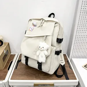Sac à dos scolaire blanc crème avec ours en peluche et épingles sur boîte de rangement