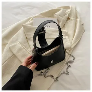 Détail d'un sac demi-lune noir avec chaîne argentée sur blazer beige, montrant l'intérieur