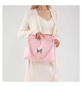 Détail du sac seau rose en PU souple avec design plissé et accent papillon argenté