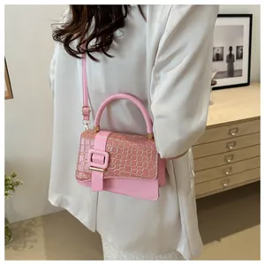 Lifestyle shot of a pink crossbody bag with crocodile texture on white blazer
