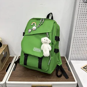 Détail du sac à dos vert avec badges de dessins animés et un porte-clé ours en peluche