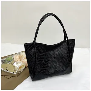 Close-up of black crocodile-embossed faux leather texture on the large tote bag
