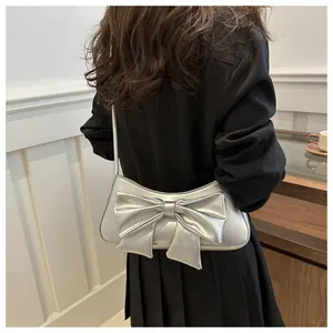 Bolso plateado con lazo y acabado metálico con textura de cocodrilo en el modelo