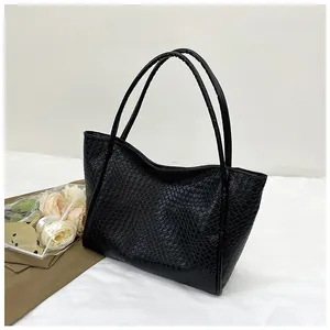 Close-up of black woven leather tote bag texture with slim handles and a minimalist look