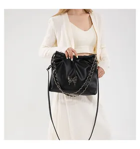 Détail du sac seau froncé noir avec logo papillon en métal et bandoulière chaîne
