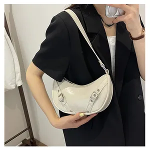 Detail view of a white crescent saddle bag with glossy finish and silver metal buckle straps