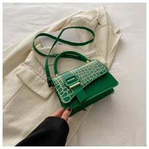 Detail of green crossbody bag with crocodile texture flap and gold buckle on a blazer