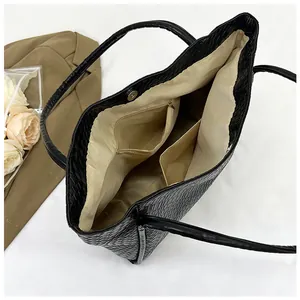 Detail view of the black woven tote bag showing beige inner lining with pockets and magnet