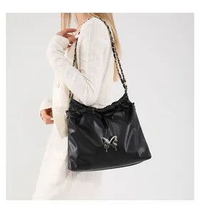 Detail of black pleated bucket bag with silver butterfly accent and chain strap