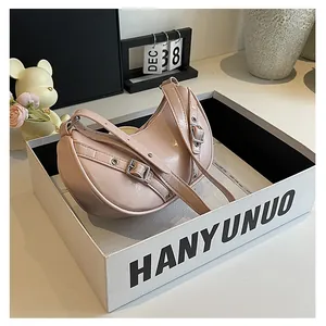 Detail view of pink saddle bag with glossy leather and silver metal eyelets in a gift box