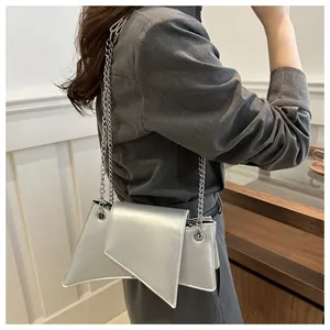 Bolso bandolera plateado con cadena y diseño de solapa asimétrica usado por una modelo