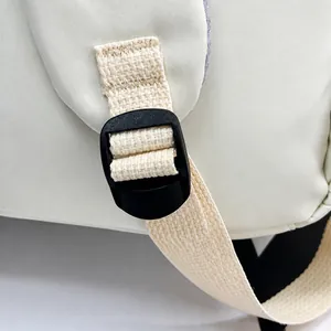 Détail de la boucle noire réglable et de la sangle tissée sur le sac à dos crème minimaliste