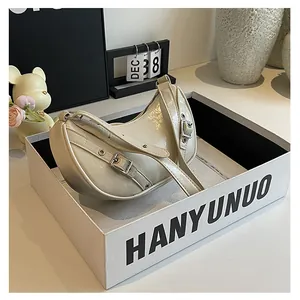 Detail view of cream saddle bag with metal buckle strap inside a premium gift box