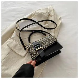 Detail of black leather crossbody bag featuring gold crocodile texture and square buckle
