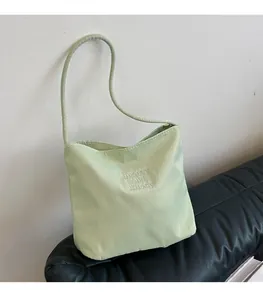 Detail of light green nylon shoulder bag with white 'pretty and liberty' embroidery