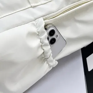 Détail d'un sac à dos blanc matelassé avec poche latérale à cordon et un smartphone