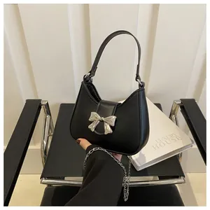 Détail du sac à main croissant en cuir noir orné d'un nœud métallique argenté et d'une chaîne