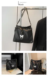 Detail of black pleated bucket bag with silver butterfly clasp and chain strap