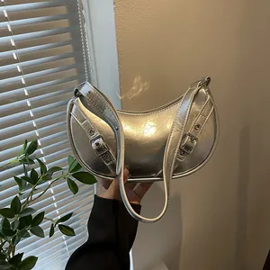 Metallic silver saddle bag with belt buckle details shown in a modern lifestyle setting