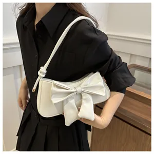 Detalle de bolso de hombro blanco con un lazo decorativo grande y nudo lateral