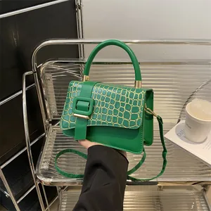 Chic green crocodile embossed crossbody bag with gold stitching and top handle