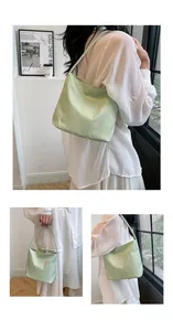 Detail of light green nylon shoulder bag with white embroidery and thin strap on a model