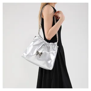 Sac seau métallisé argenté avec papillon et bandoulière chaîne porté par un mannequin