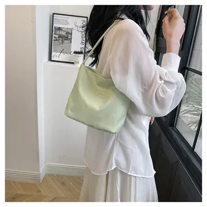 Close-up of light green nylon shoulder bag with proudly and liberty embroidered text