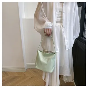 Close-up of light green nylon bag with pretty and lively embroidery and silk handle