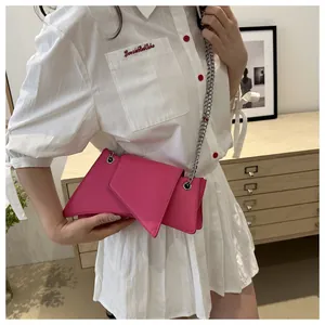 Detalle del bolso geométrico rosa fucsia con cadena plateada lucido por modelo en casa acogedora