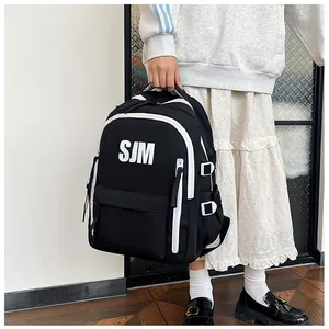Detail eines schwarzen Schulrucksacks mit weißen SJM-Buchstaben und Seitenschnallen