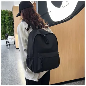 Sac à dos noir minimaliste grande capacité porté par un mannequin dans un intérieur