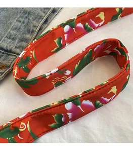 Dettaglio della tracolla in nylon rosso con motivi floreali e cuciture rifinite