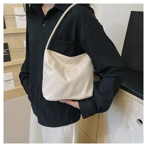 Close-up of cream white nylon shoulder bag featuring elegant embroidery detail