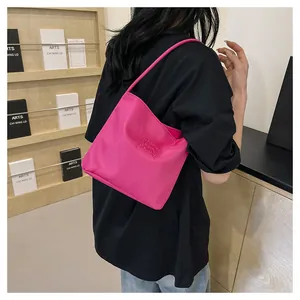 Fashionable pink nylon shoulder bag with Pretty and Liberty embroidery worn by a model