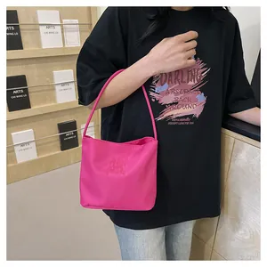 Detailed view of pink nylon shoulder bag with 3D embossed text embroidery and long strap