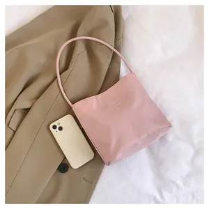Pink nylon bucket bag with pretty and liberty embroidery shown on a khaki blazer