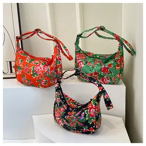 Vista dettagliata di tre borse in nylon con vivaci motivi floreali su piedistalli bianchi