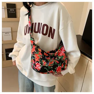 Dettaglio della borsa a tracolla in nylon a fiori indossata su una felpa bianca casual