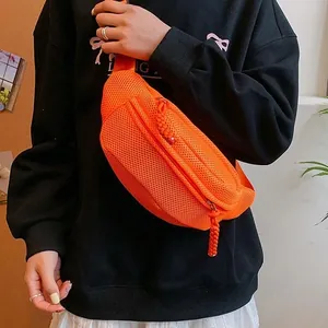 Women's bright orange mesh chest bag with adjustable strap shown on model over black hoodie