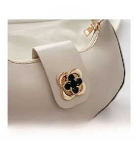 Detailed shot of the elegant four-leaf clover metal buckle on the cream crescent bag