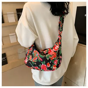 Dettaglio borsa a mezzaluna in nylon con vivaci motivi floreali tradizionali su nero